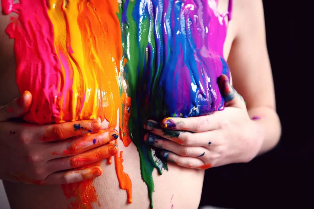 image of a woman's torso covered in the Gay Pride rainbow paint colors